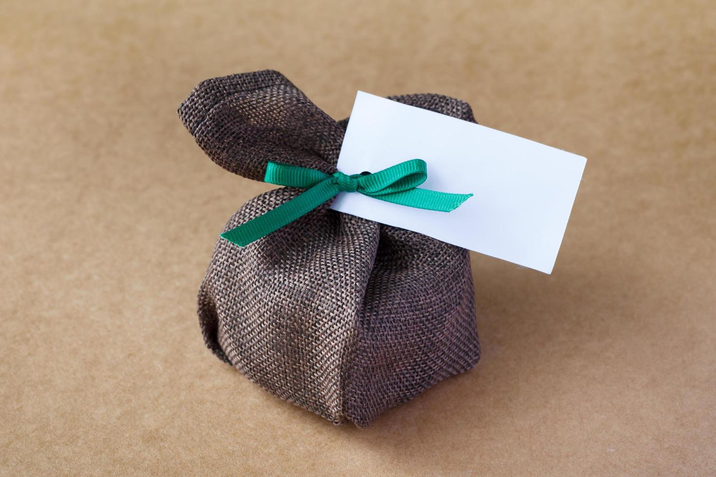 sack gift bag with ribbon bow on brown background photo