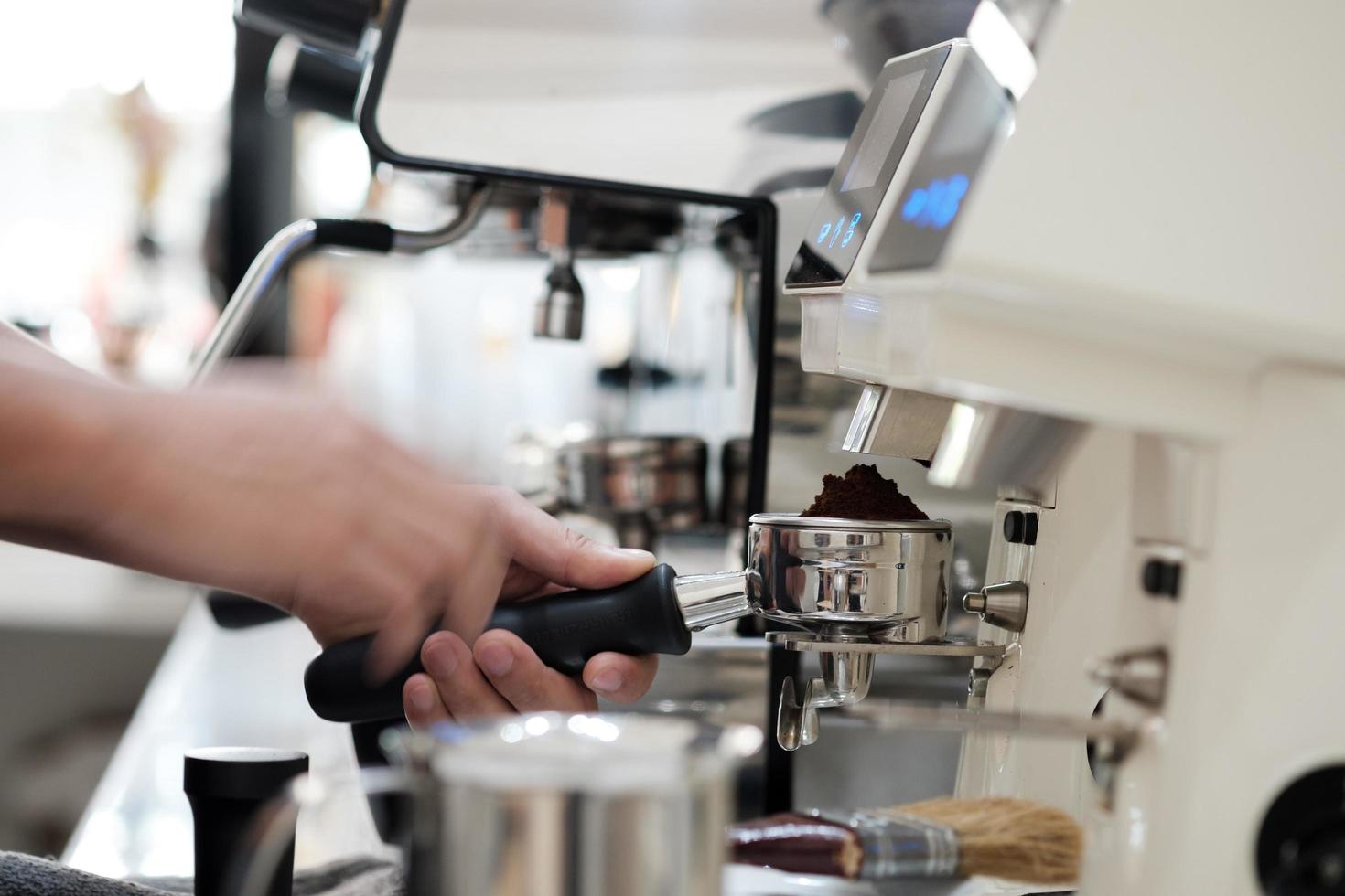 man holding portafilter loaded with grinded coffee and preparing fresh espresso photo