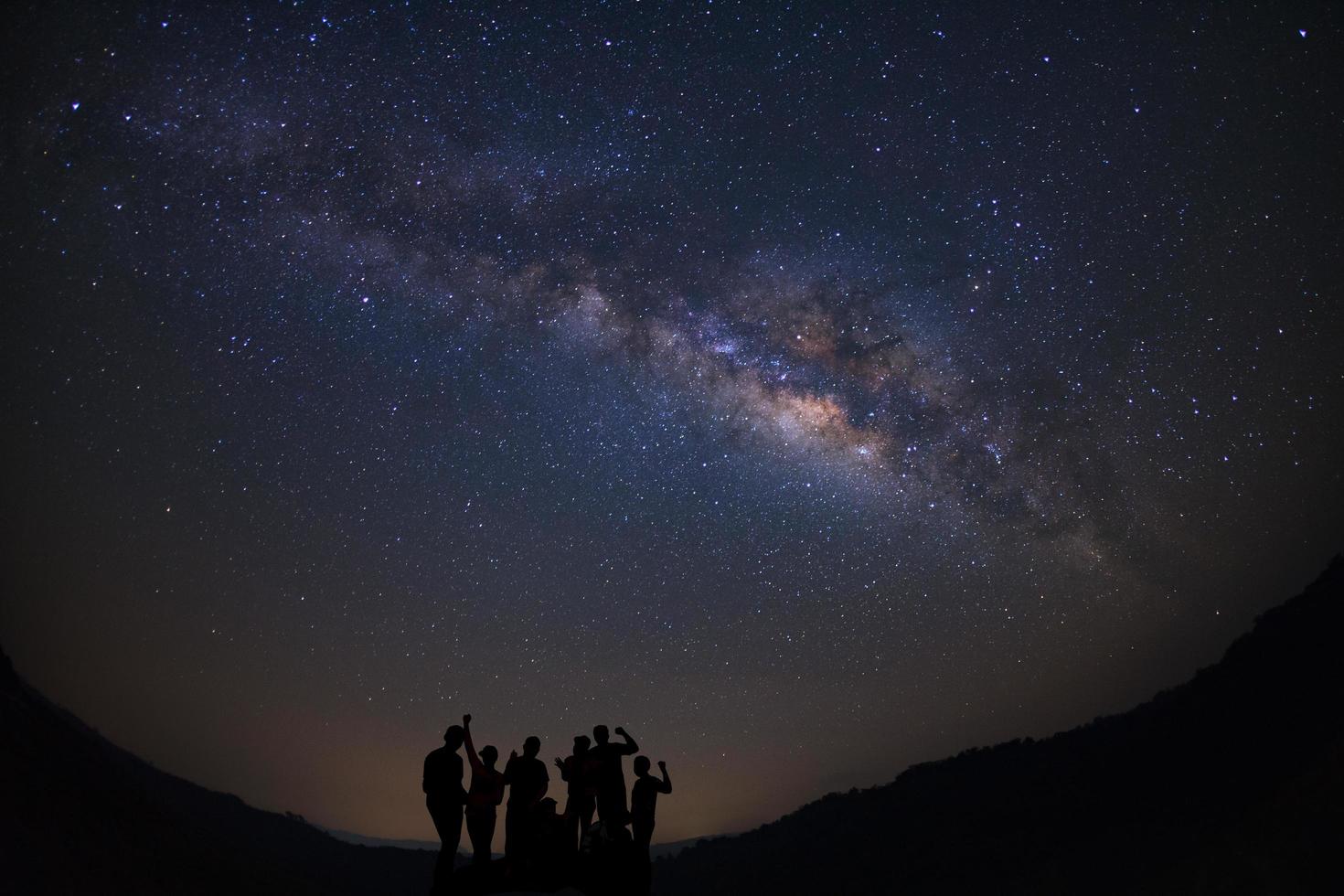 Landscape with milky way, Night sky with stars and silhouette of happy people standing on moutain, Long exposure photograph, with grain. photo