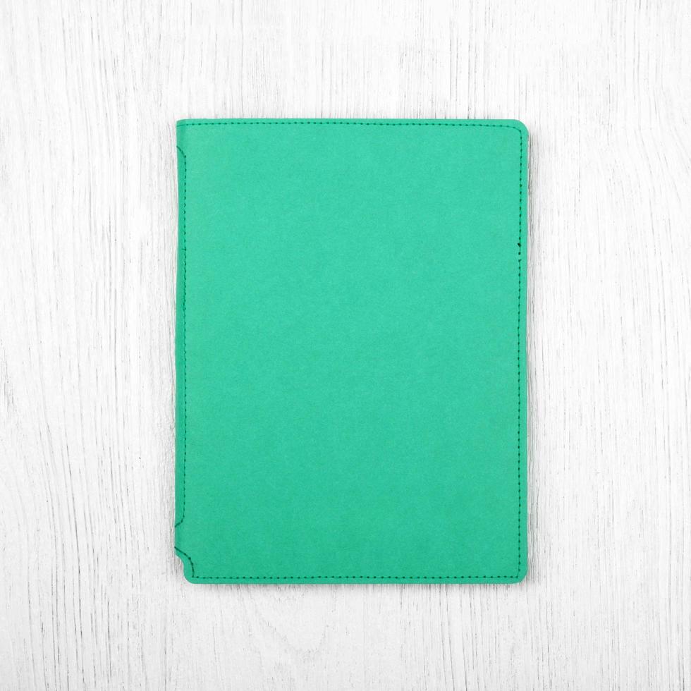 green notebook on white wooden table, top view photo