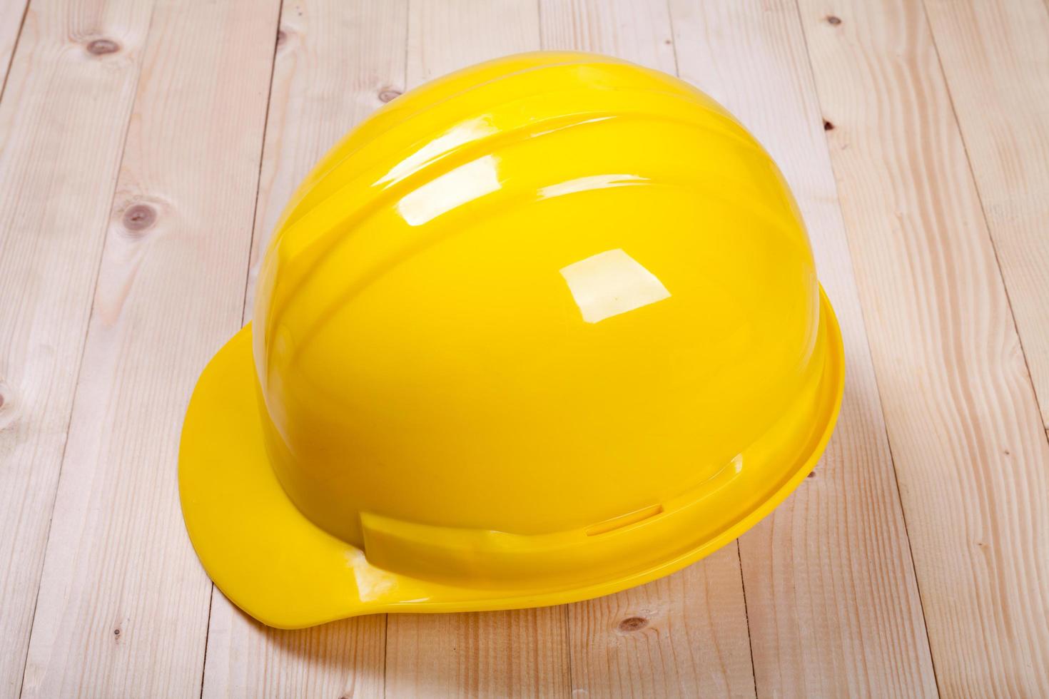 yellow hardhat architect on brown wood background photo