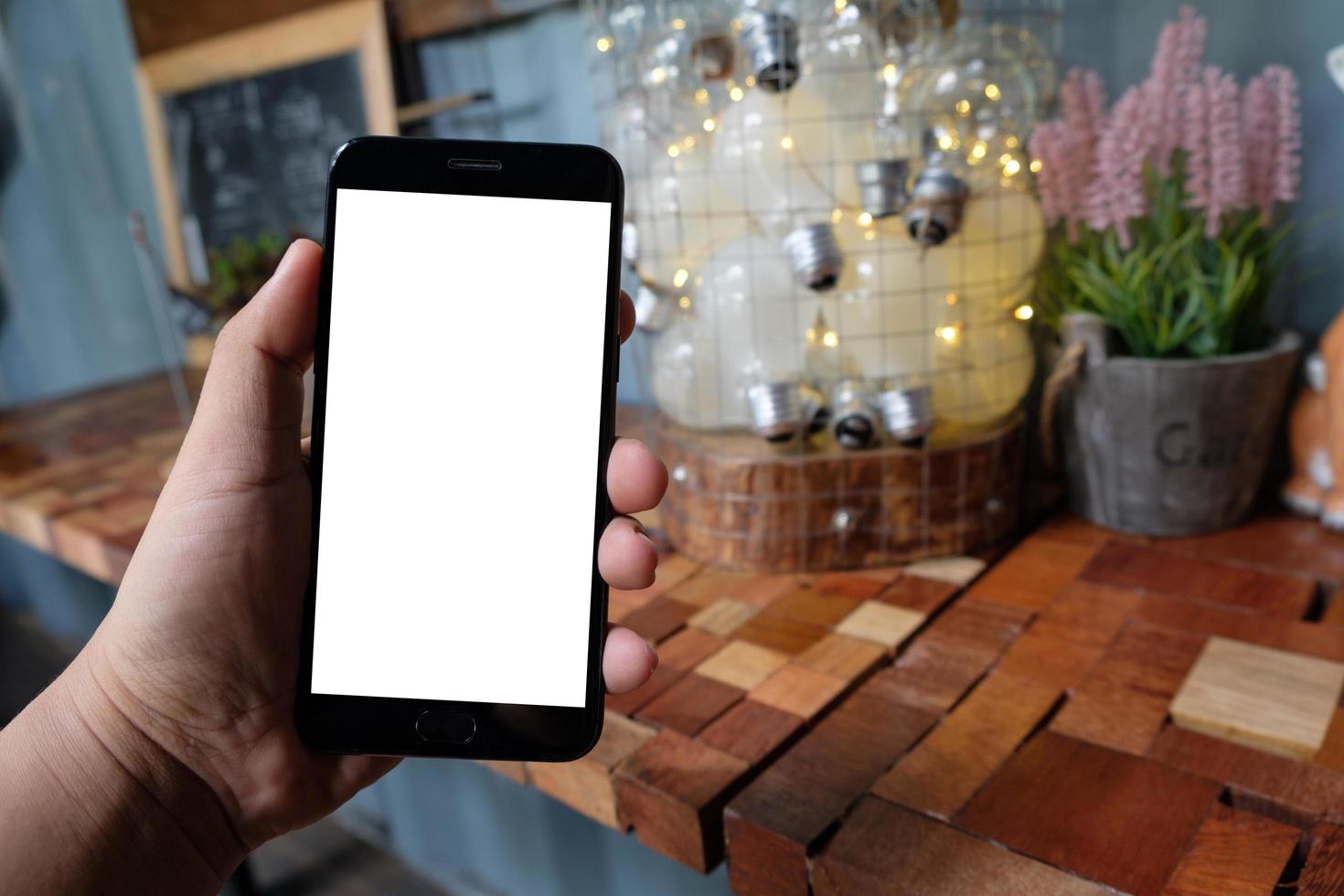 Man hands holding blank screen smartphone with blurred coffee shop background. photo
