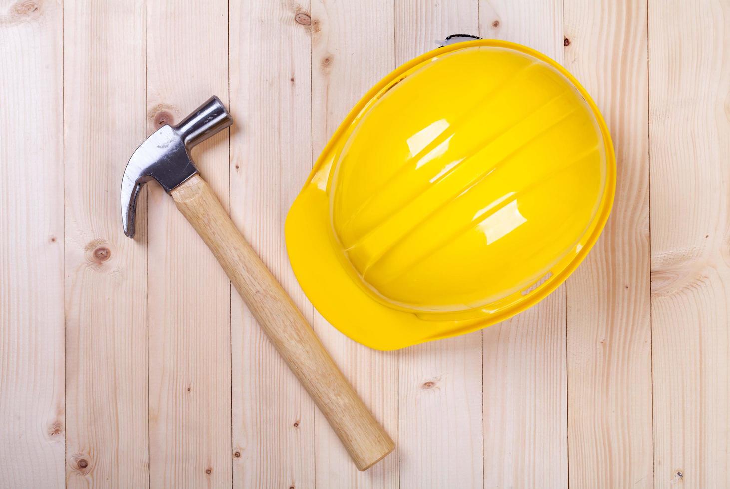 hammer and yellow hardhat on wood background photo