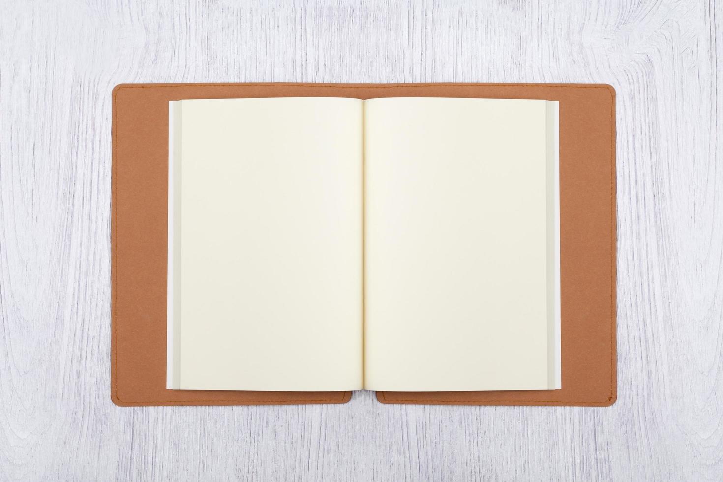 Open brown notebook on white wooden table, top view photo