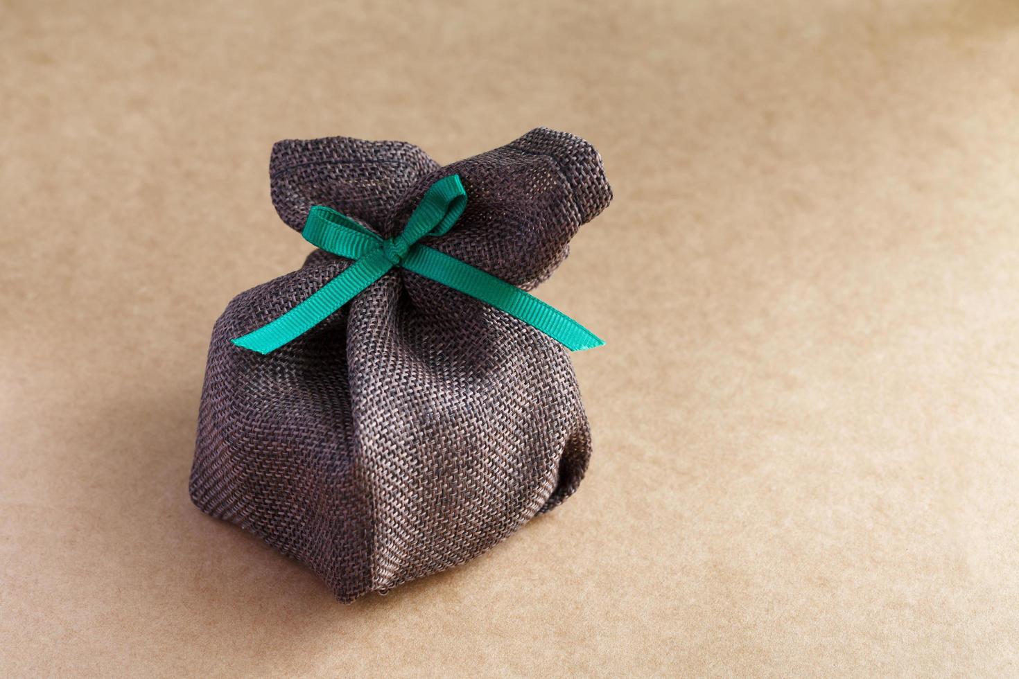 sack gift bag with ribbon bow on brown background photo