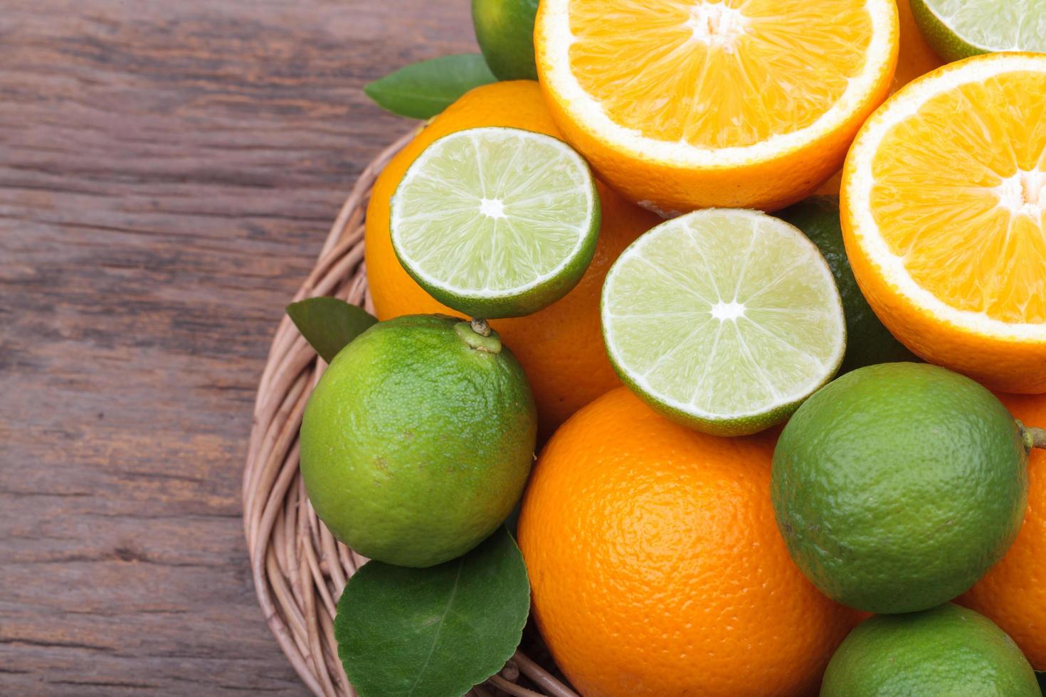 mezcla de frutas cítricas frescas en canasta sobre madera foto