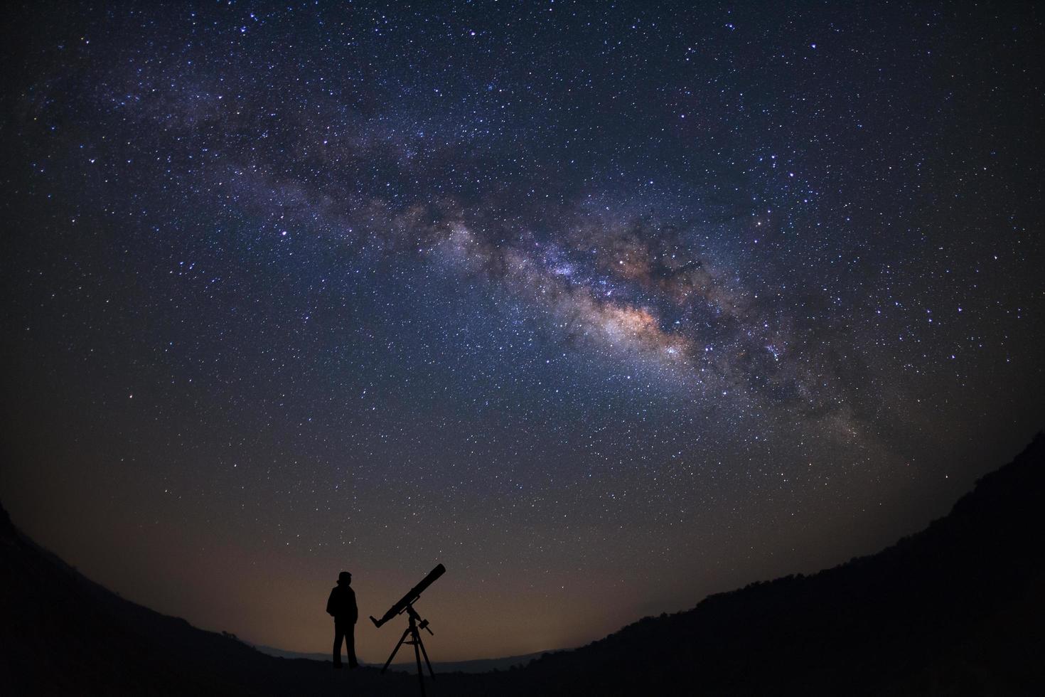 Silhouette of a standing man with telescope watching the wilky way galaxy photo