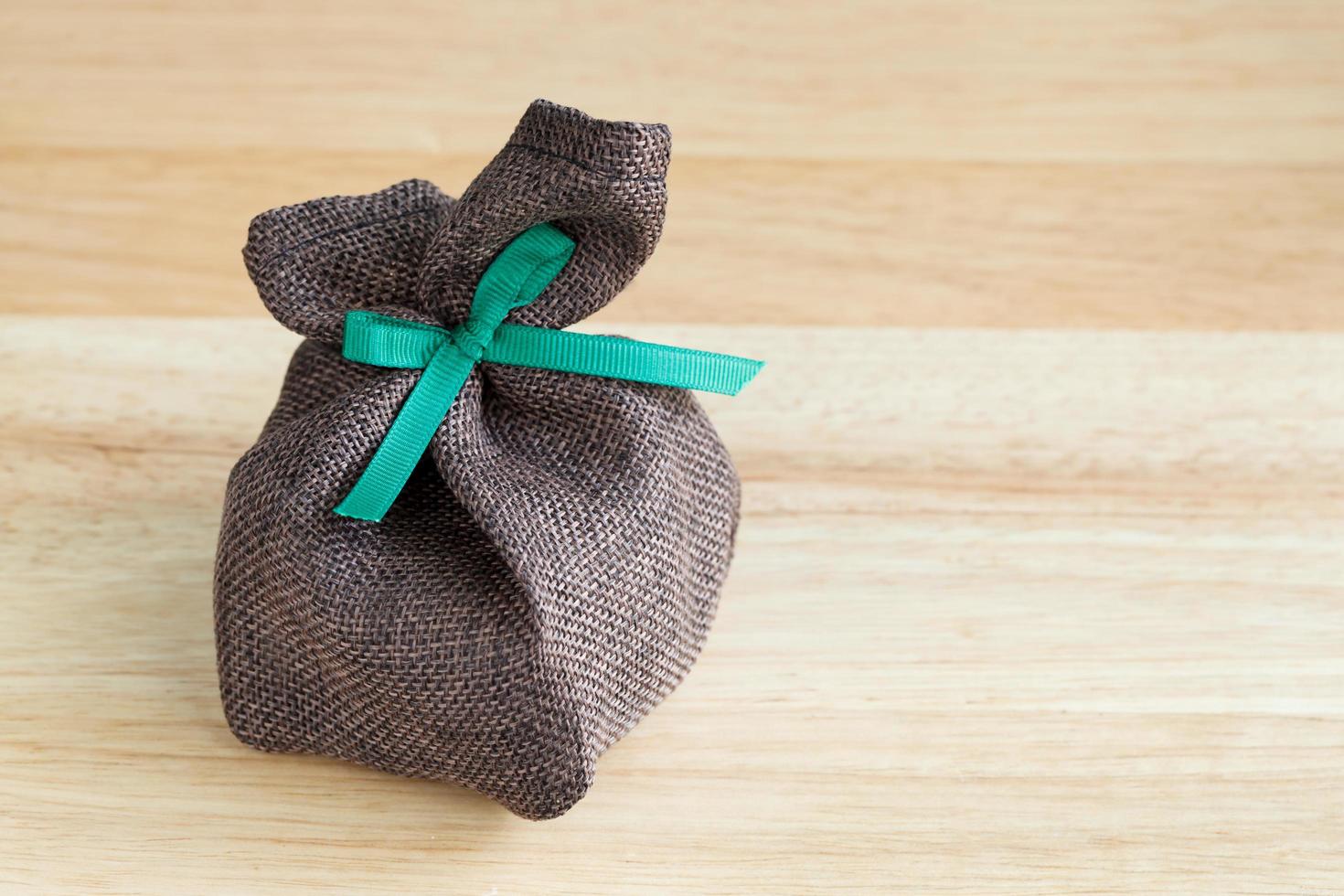 sack gift bag with ribbon bow on wood background photo