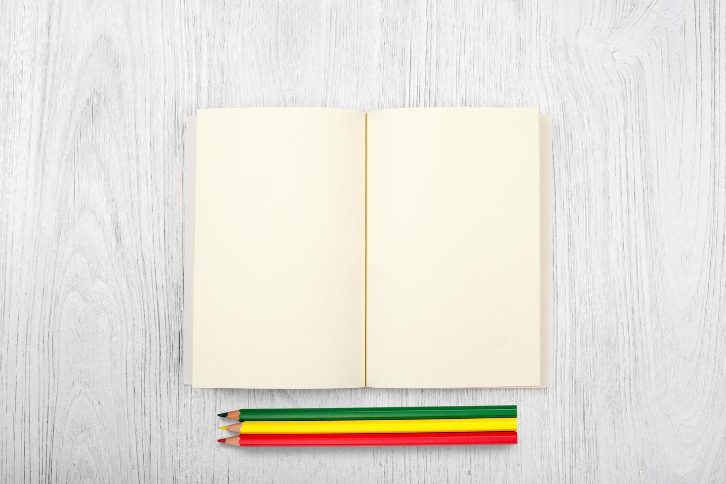 Open brown notebook and color pencil on white wooden table, top view photo
