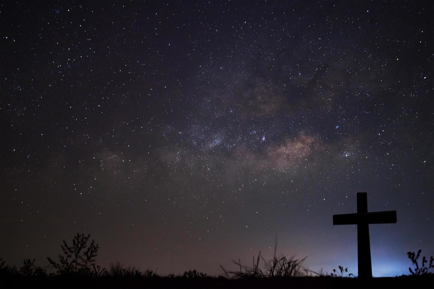 silueta de cruce sobre el fondo de la vía láctea, fotografía de larga exposición foto