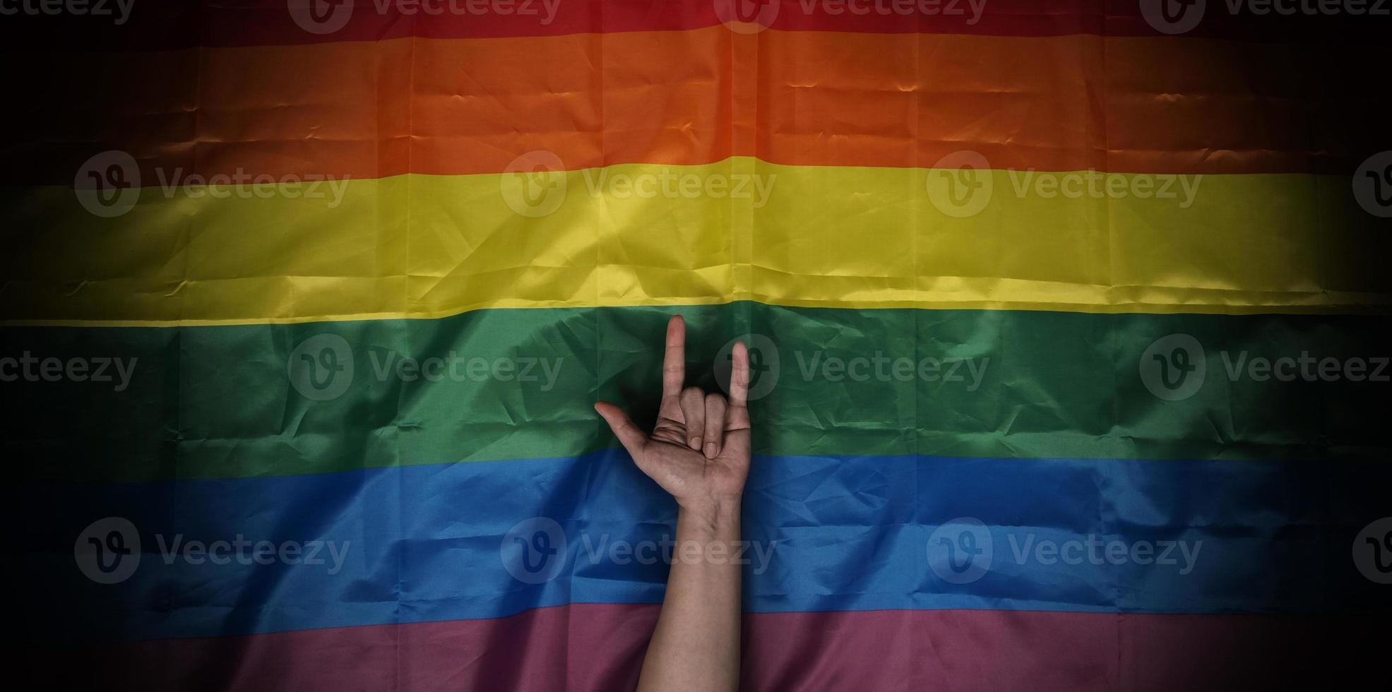 LGBTQ pride flag on black background. Lgbt rainbow flag in gay hand. photo