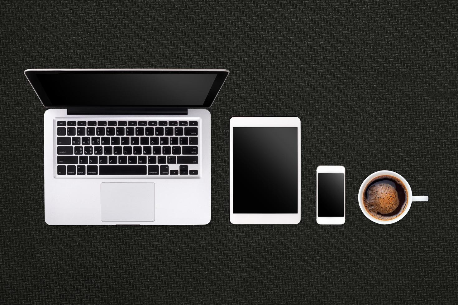 Laptop tablet smartphone  and coffee on black rubber  background with text space and copy space photo