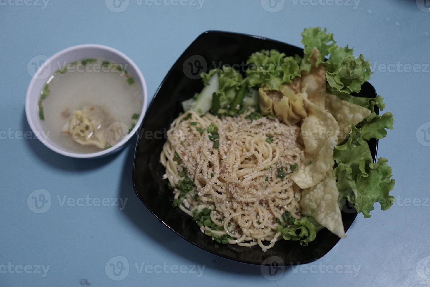 A bowl of original wonton noodles and a small bowl of Indonesian meatballs photo