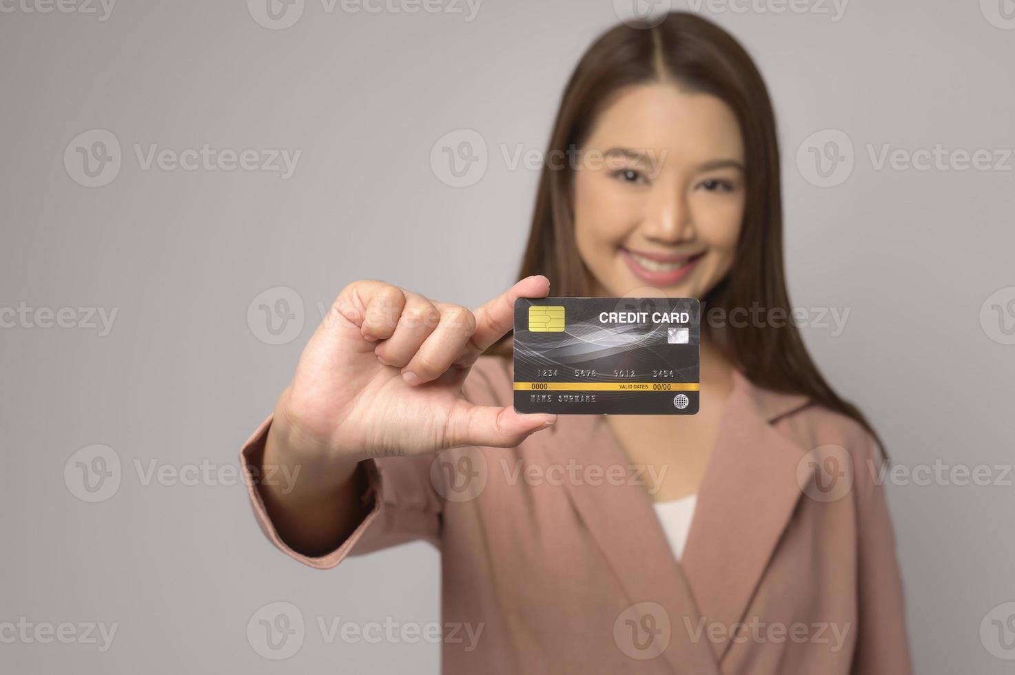 Young asian woman holding credit card over white background studio, shopping and finance concept. photo