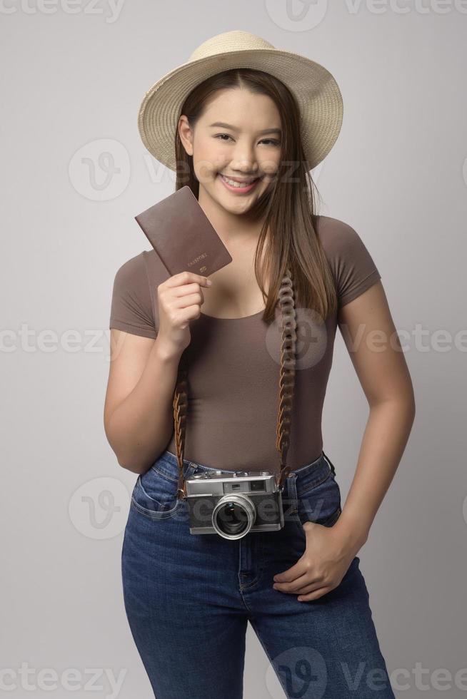 Young happy asian tourist woman over white background studio, travel and holidays concept. photo