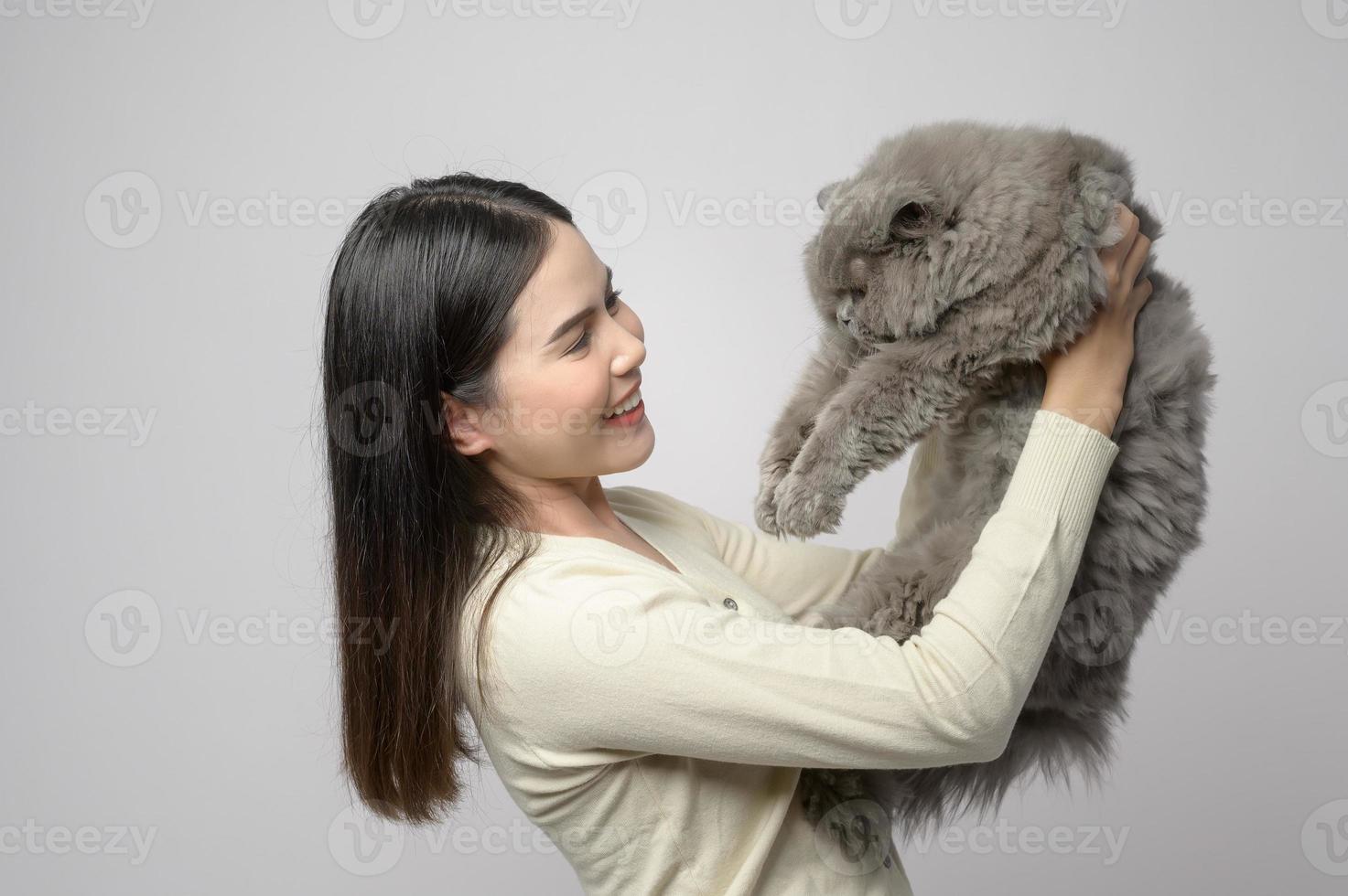 A young woman is holding lovely cat , playing with cat in studio on white background photo