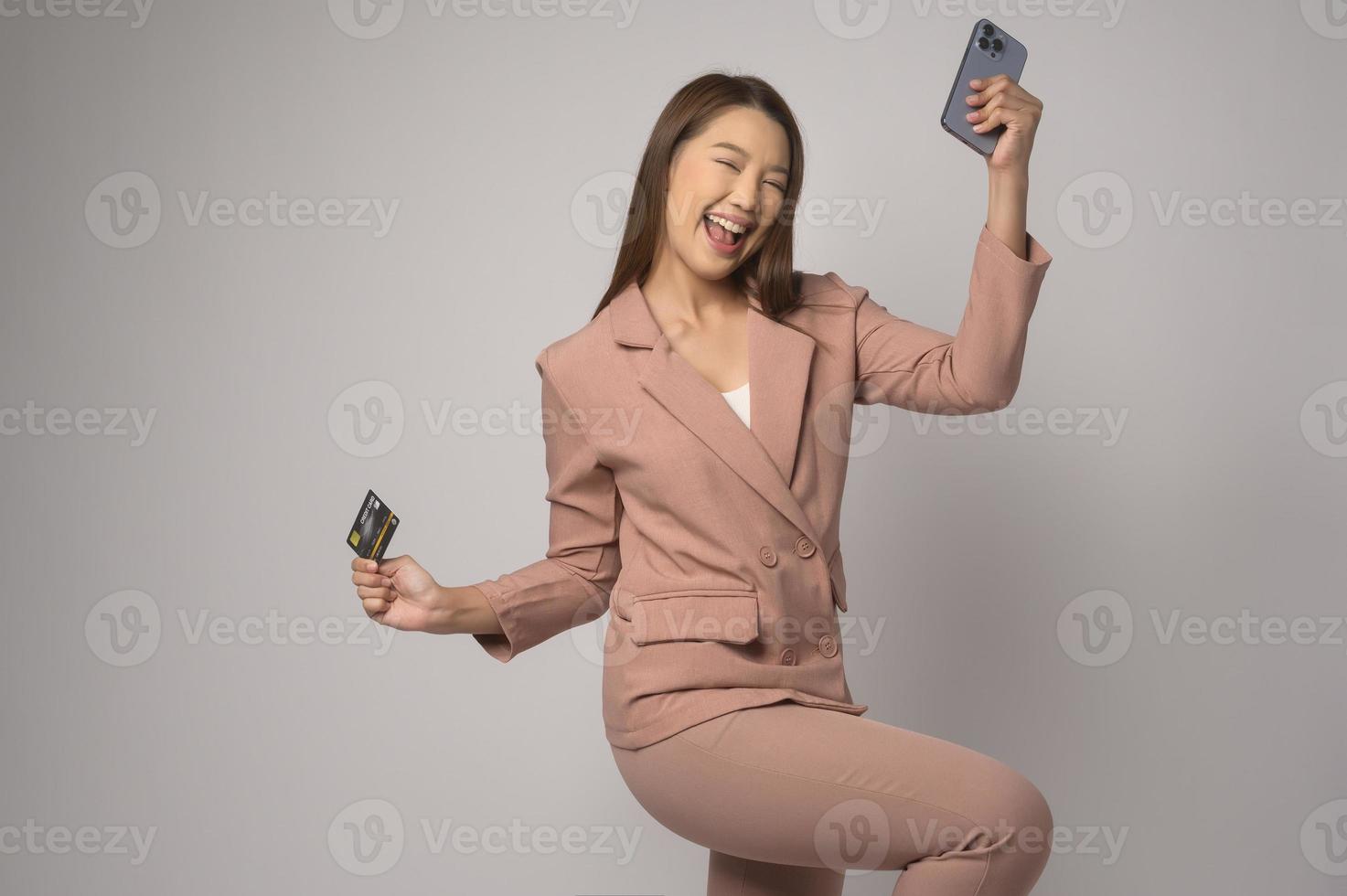 Young asian woman holding credit card over white background studio, shopping and finance concept. photo