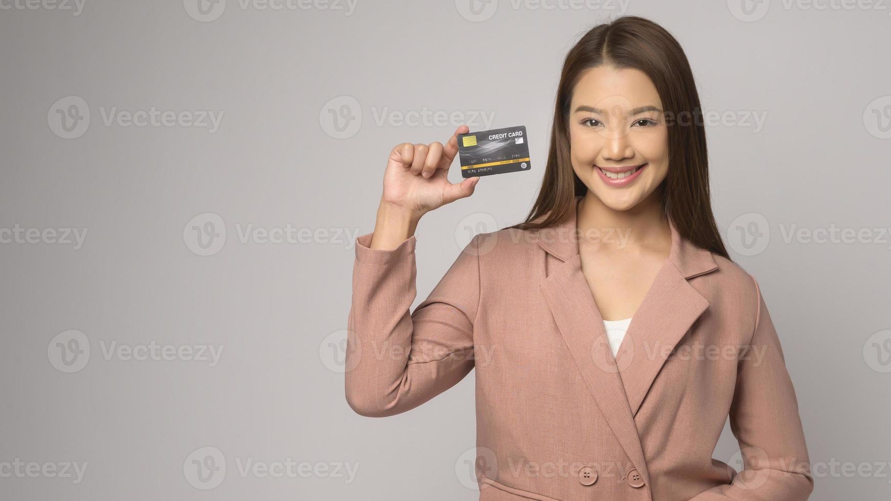 Young asian woman holding credit card over white background studio, shopping and finance concept. photo