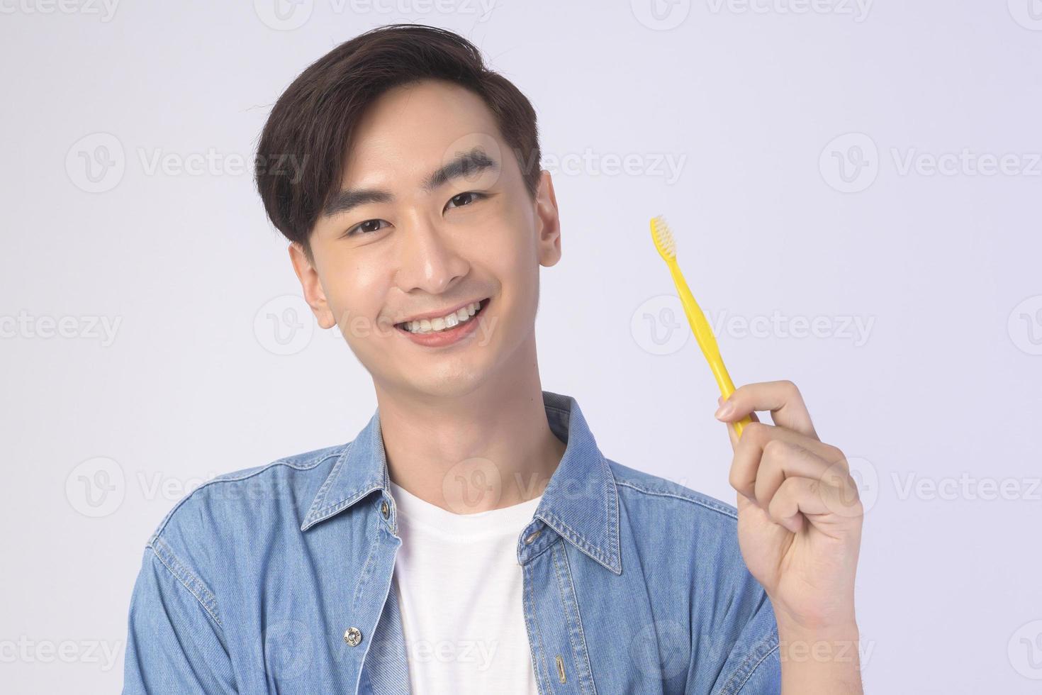 joven sonriente sosteniendo cepillo de dientes sobre estudio de fondo blanco, salud dental y concepto de ortodoncia. foto