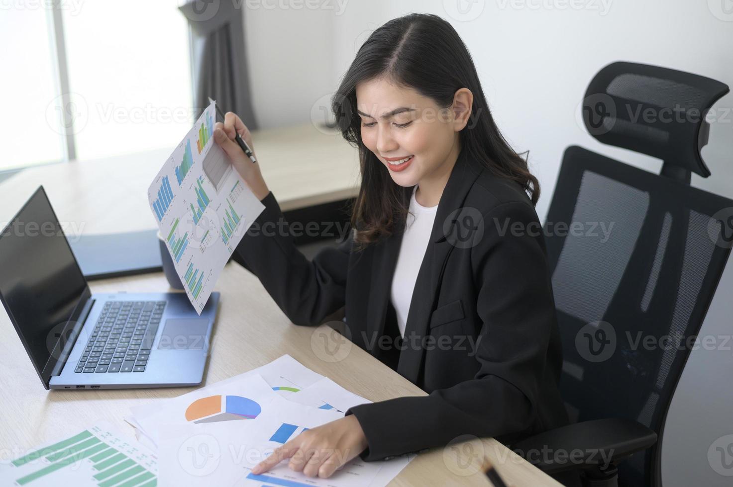 joven y hermosa mujer de negocios que trabaja en una laptop con documentos en una oficina moderna foto