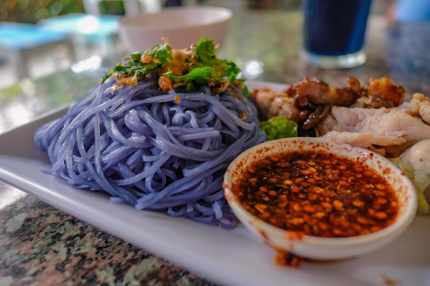 Blue pea Noodle Served Spicy sauce and pork meat top up with Green Vagatable photo