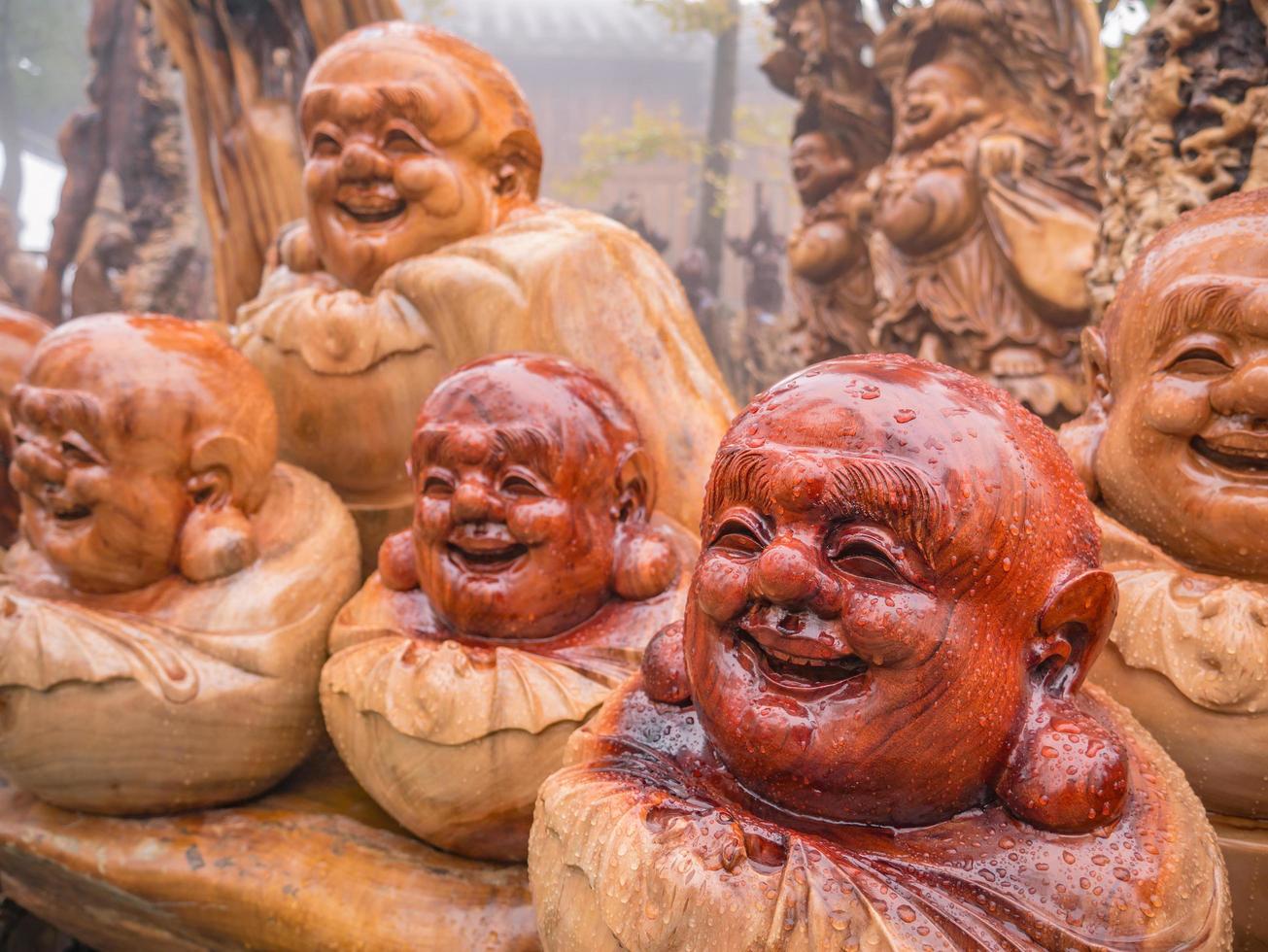 estatua de buda sonriente de madera esculpida con gota de lluvia en la estatua en la montaña tianzi en el parque forestal nacional de zhangjiajie en el distrito de wulingyuan, ciudad de zhangjiajie, china. foto