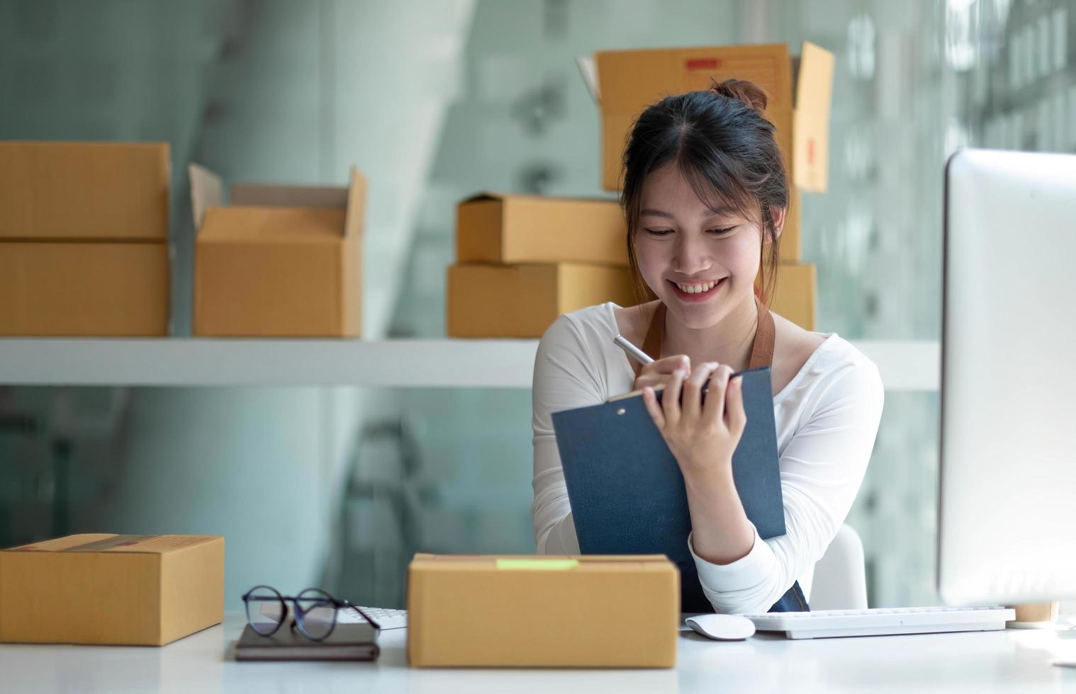 Starting small businesses SME owners female entrepreneurs Use a laptop or notebook to receive and review orders online to prepare to pack boxes, sell to customers, SME online business ideas. photo