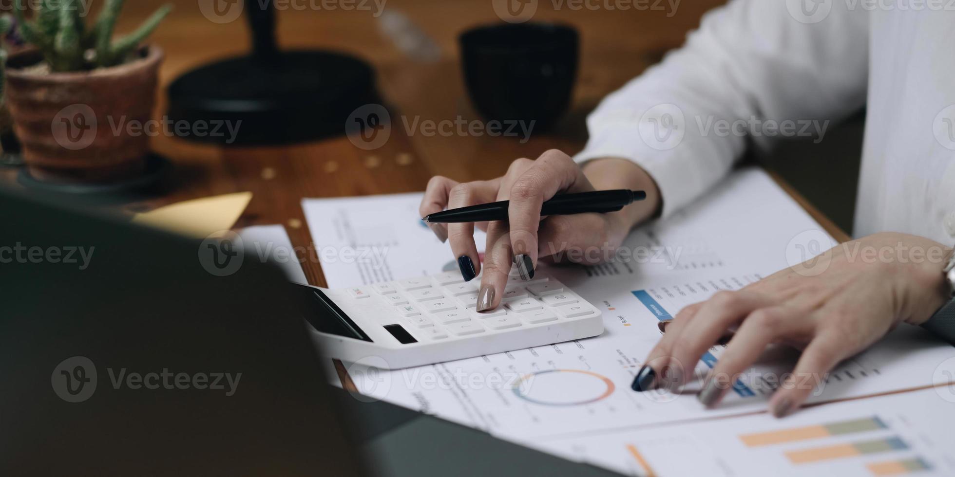 Close up Business woman using calculator and laptop for do math finance on wooden desk in office and business working background, tax, accounting, statistics and analytic research concept photo