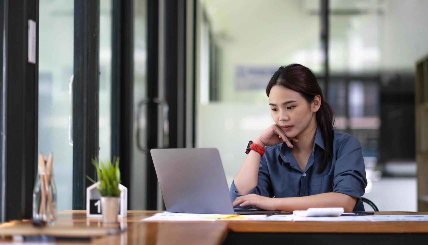 Portrait of Asian young female working on laptop at office photo