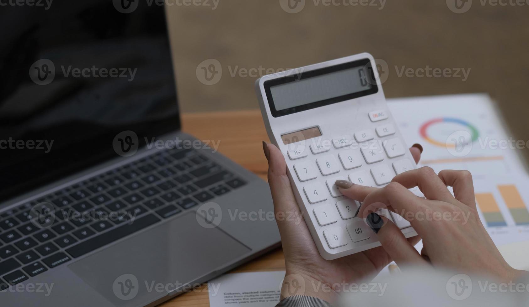 Close up Business woman using calculator and laptop for do math finance on wooden desk in office and business working background, tax, accounting, statistics and analytic research concept photo