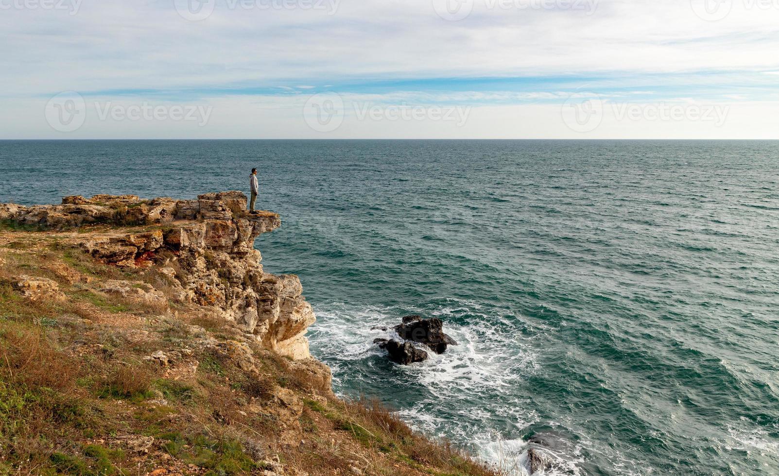 A man enjoys a beautiful sea view from the top of a cliff. photo