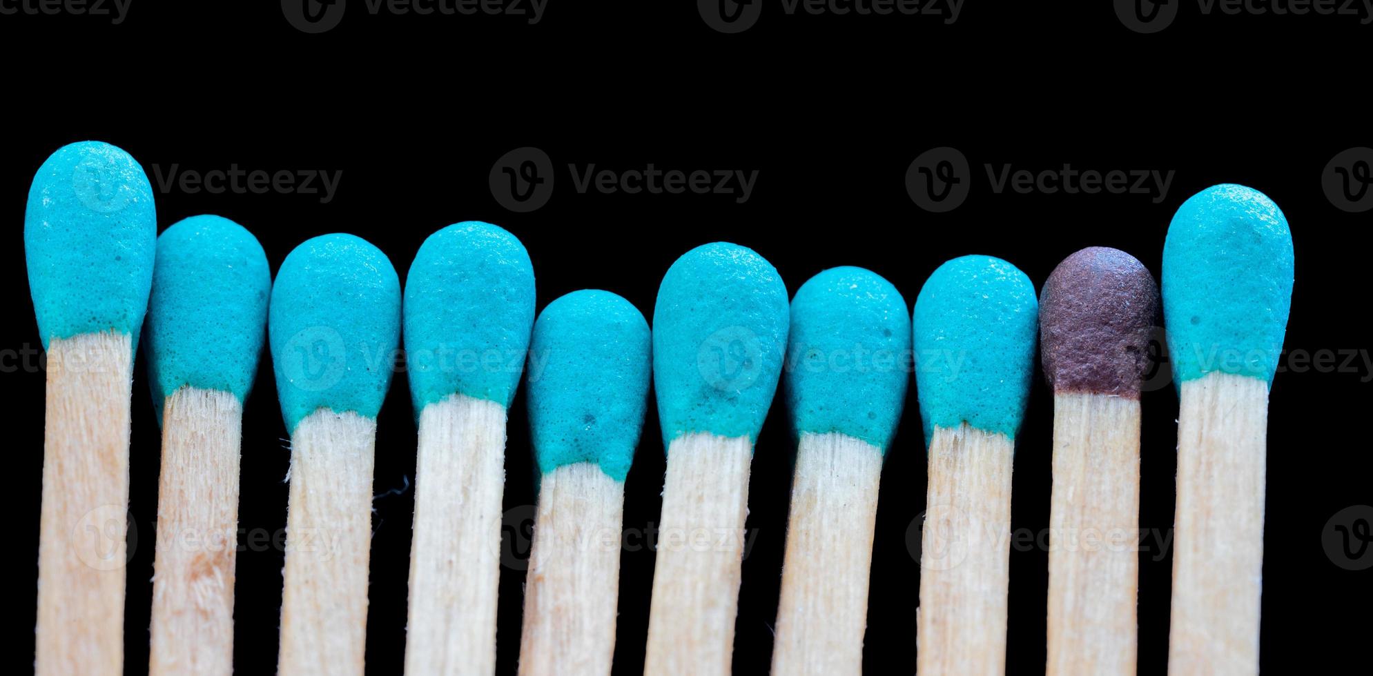 a row of blue matches and one different on black background. Concept photo