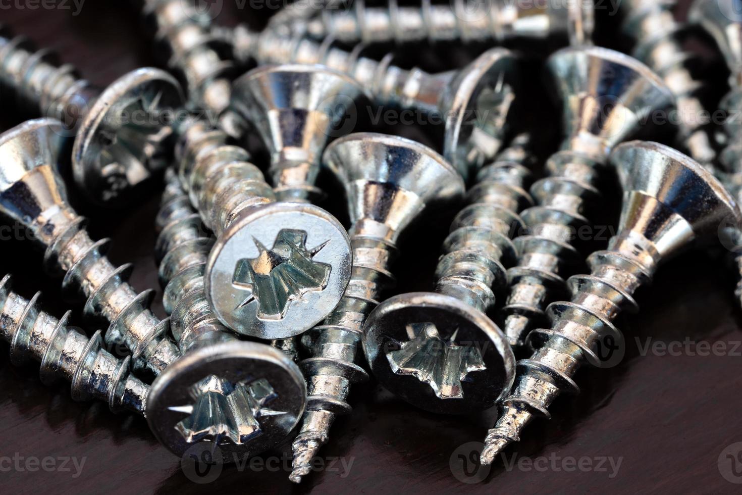A pile of screws on the black table. Close up photo