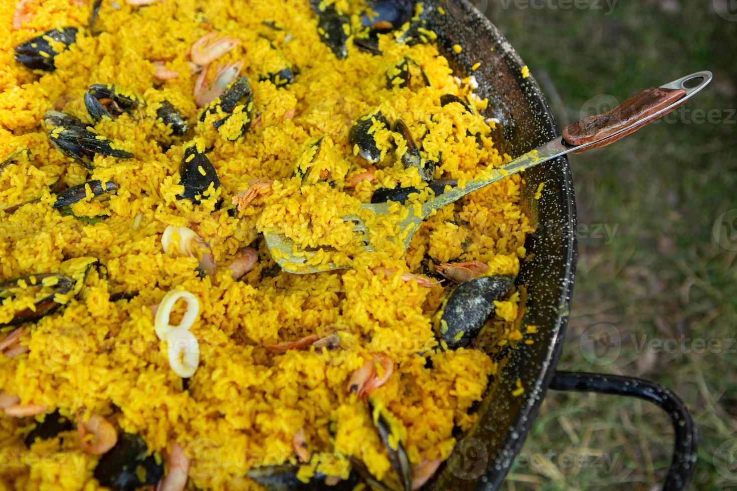 paella comida tradicional española. paella preparada en una sartén grande en la calle en llamas foto