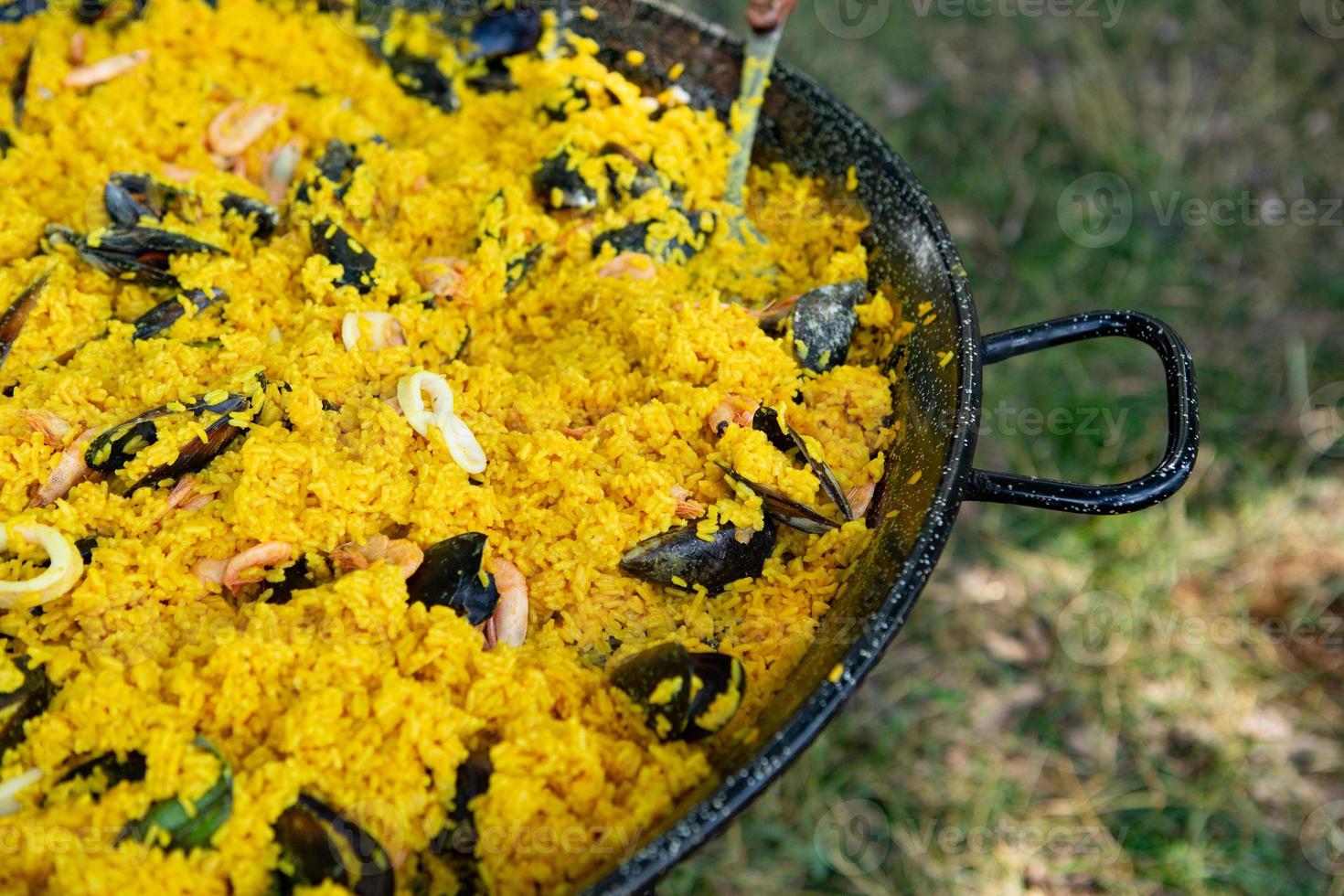 paella comida tradicional española. paella preparada en una sartén grande en la calle en llamas foto