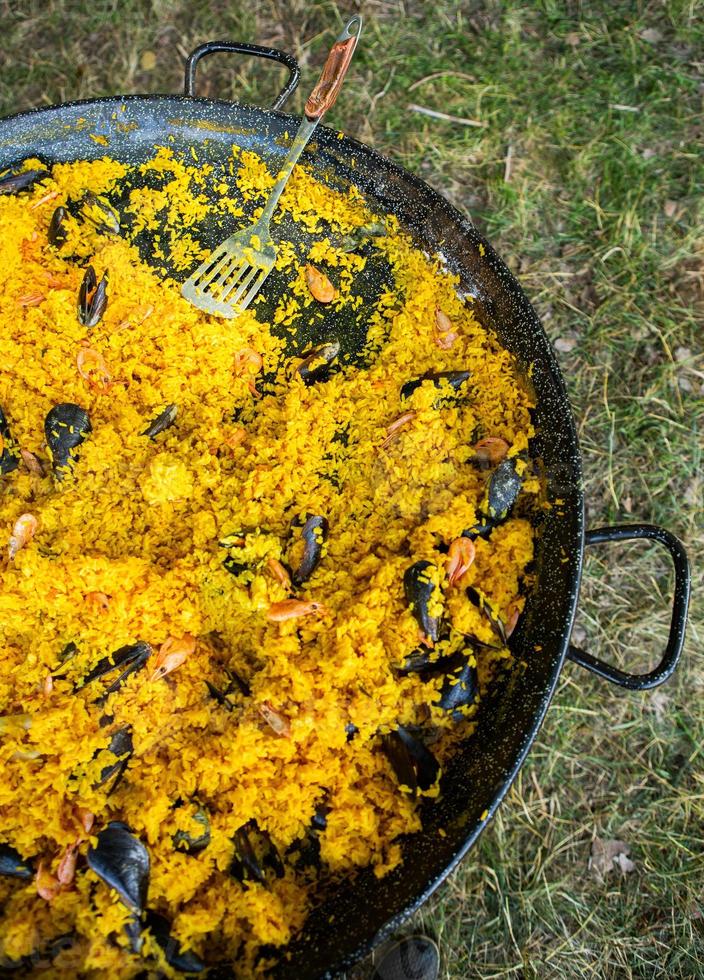 paella comida tradicional española. paella preparada en una sartén grande en la calle en llamas foto