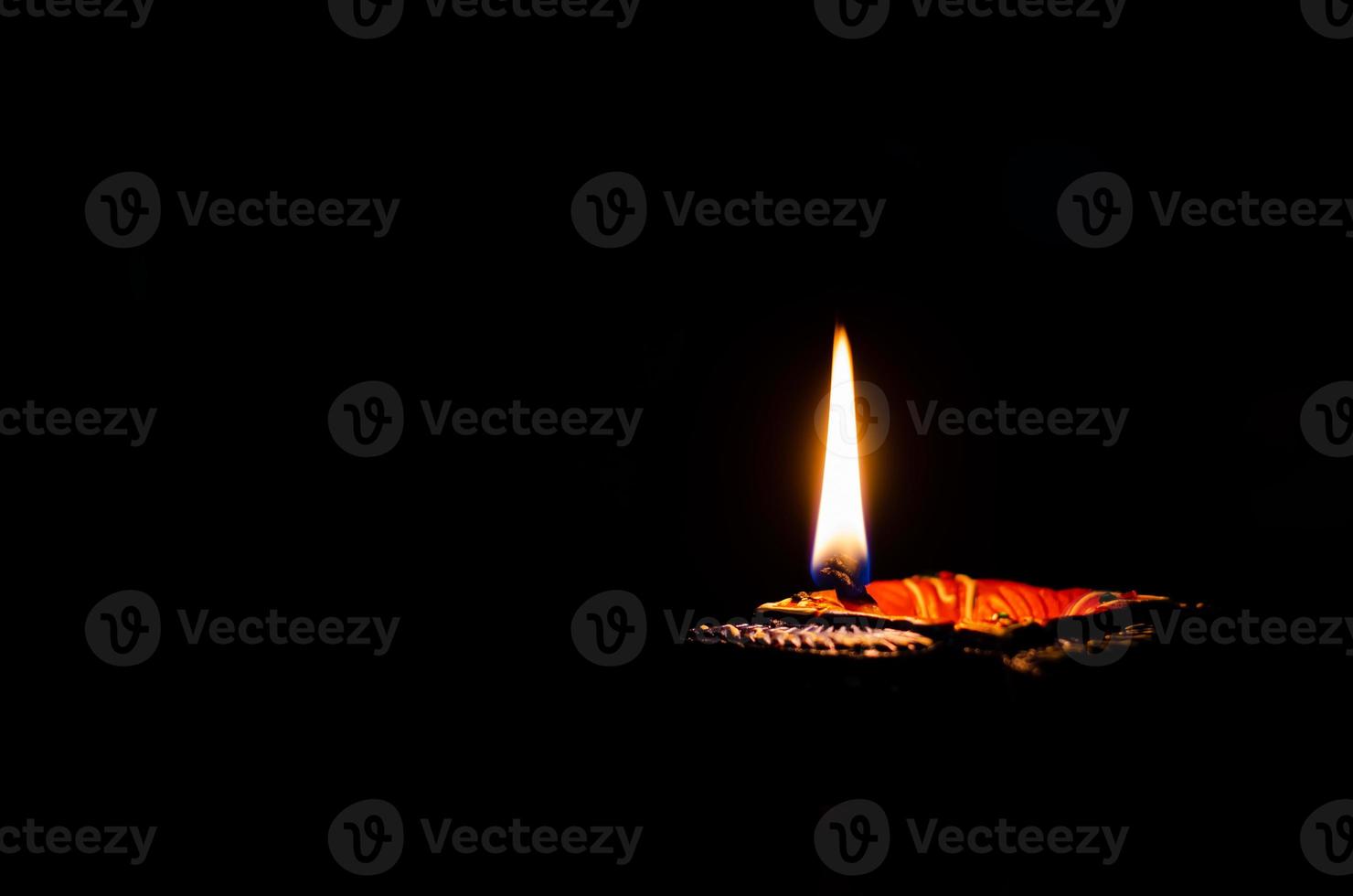 Selective focus on flame of clay diya lamp lit on dark background. Diwali festival concept. photo