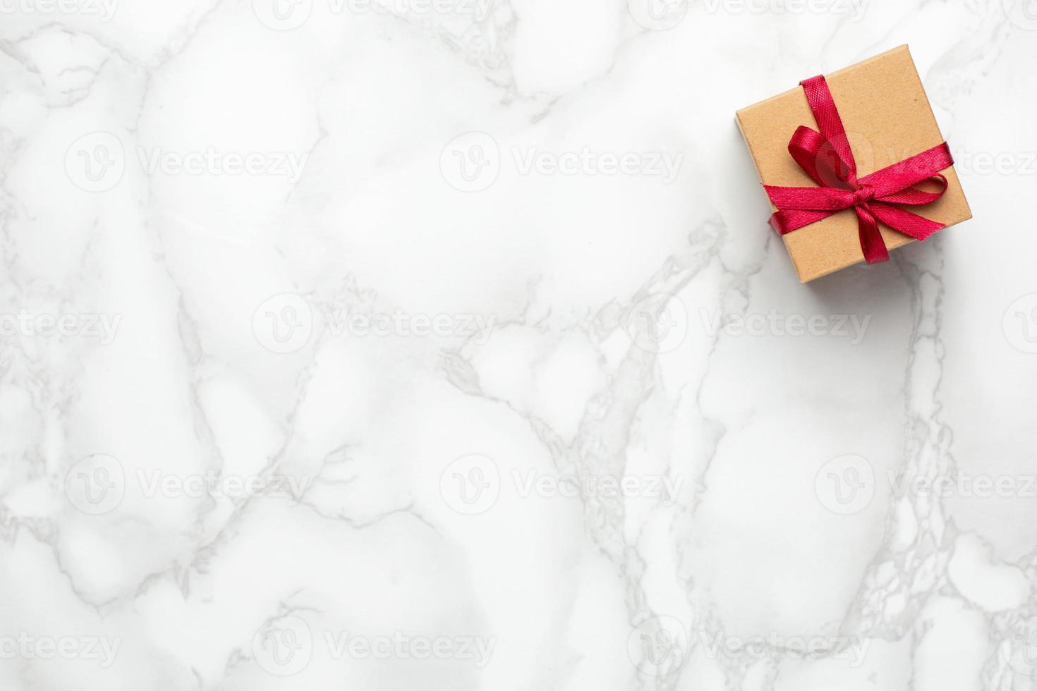 Present with pink ribbon on marble background with copyspace. Minimalistic composition for the holidays photo