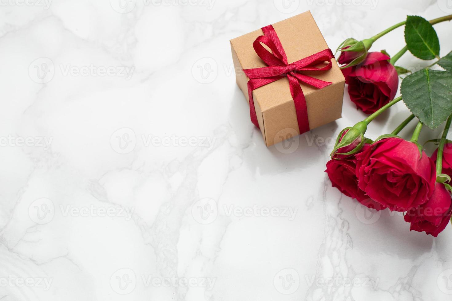 Present with pink ribbon and roses on marble background with copyspace. Minimalistic composition for the holidays. photo