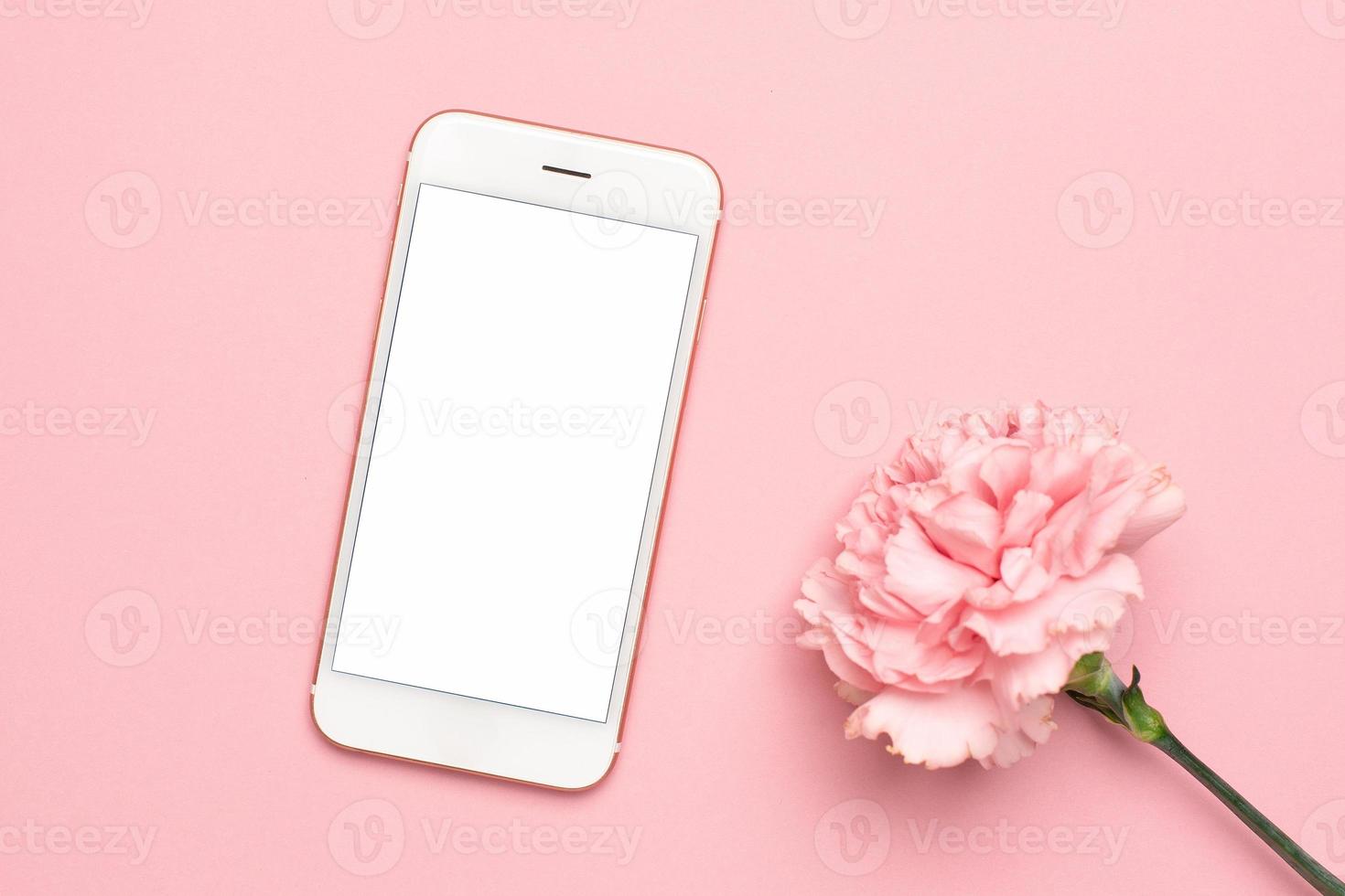 Mobile phone with pink carnation flower on a marble background photo