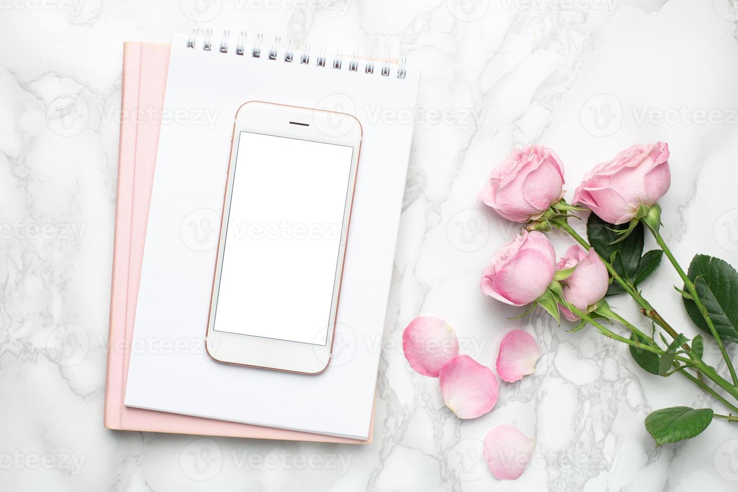 Mobile phone with pink roses flowers on marble background.Minimalistic composition for the holidays,valentines day and womens day. photo