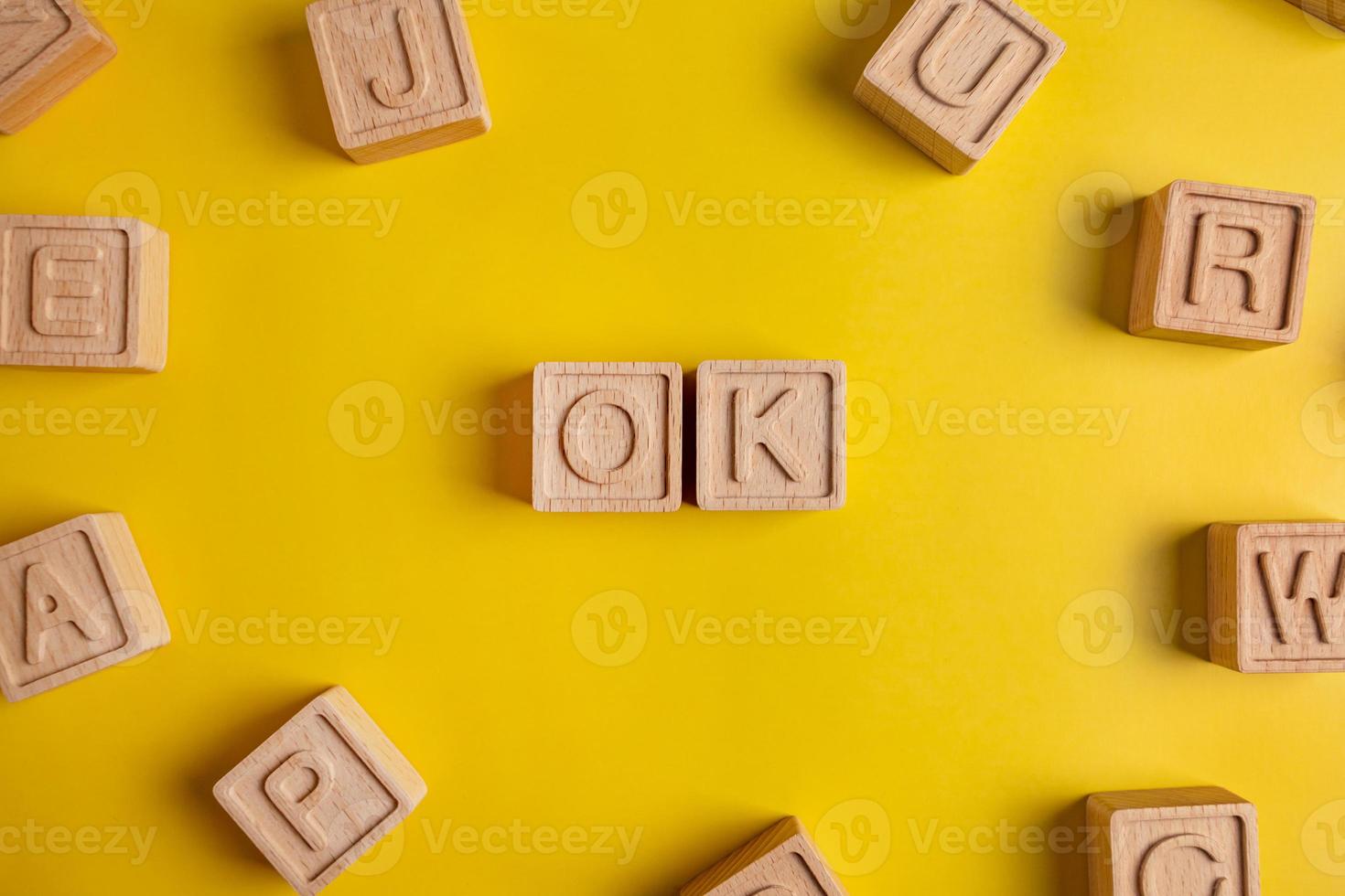 The word ok is made up of square wooden cubes with letters on a yellow background photo