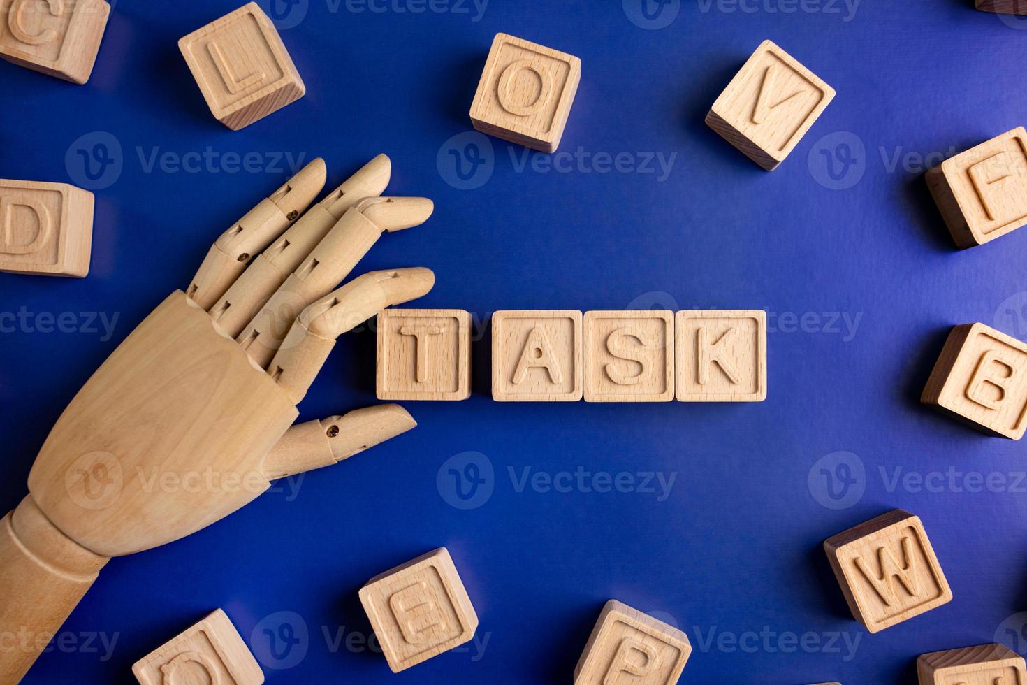 TASK the word on wooden cubes with wooden hand on blue background . Business and finance concept photo