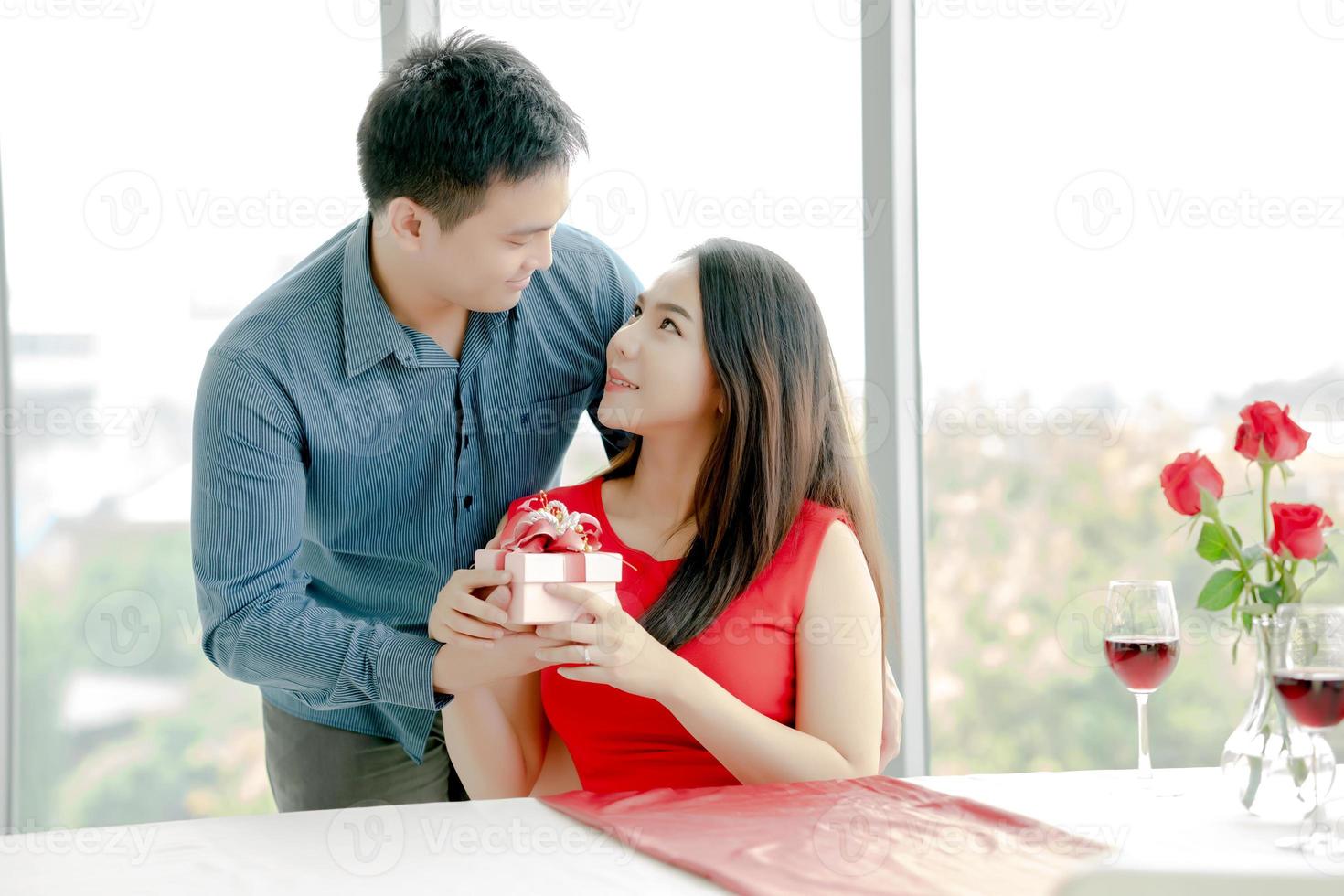 hombre dando a su novia caja de regalo con cinta roja foto