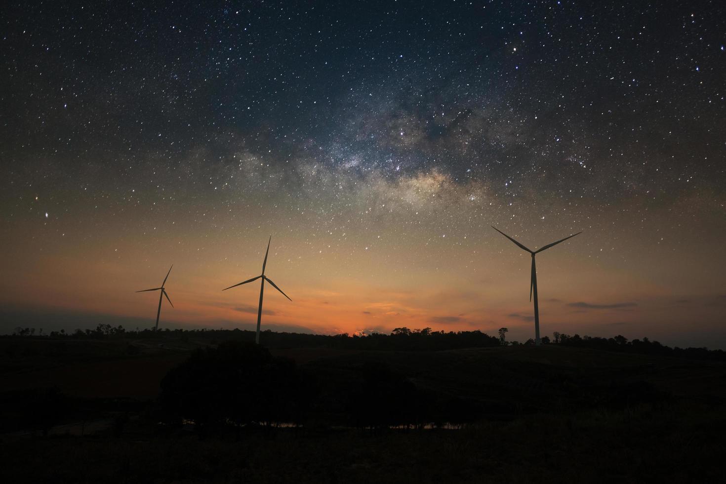 Milky way galaxy over wind turbine clean energy photo