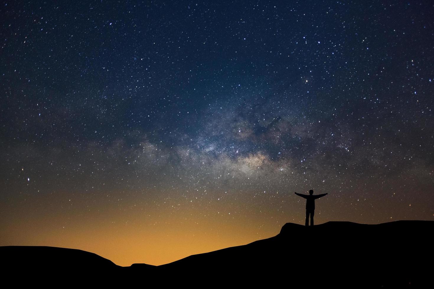 Landscape with milky way, Night sky with stars and silhouette of happy people standing on the mountain, Long exposure photograph, with grain photo