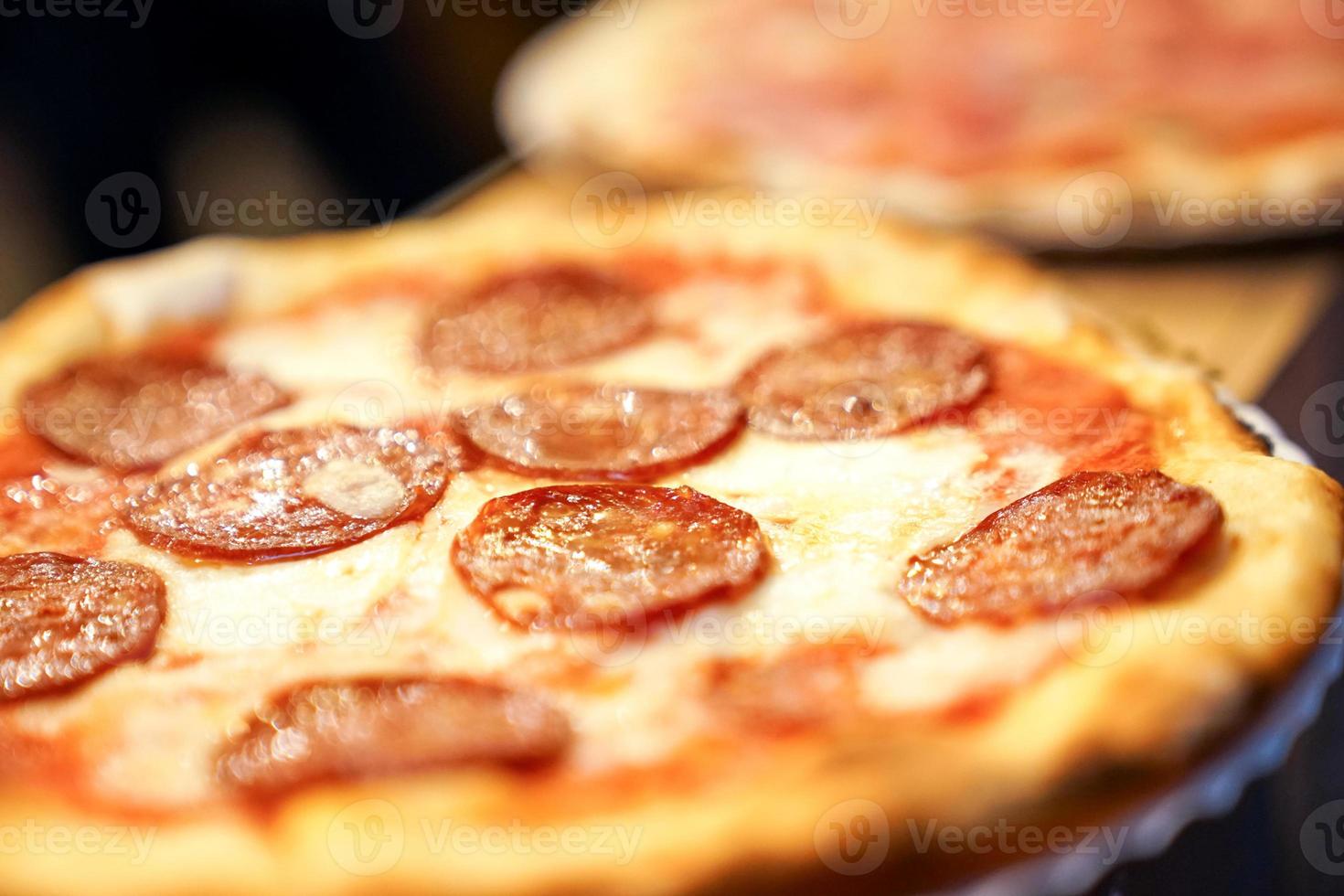 close up mini size pepperoni cheesy pizza on paper disk. photo