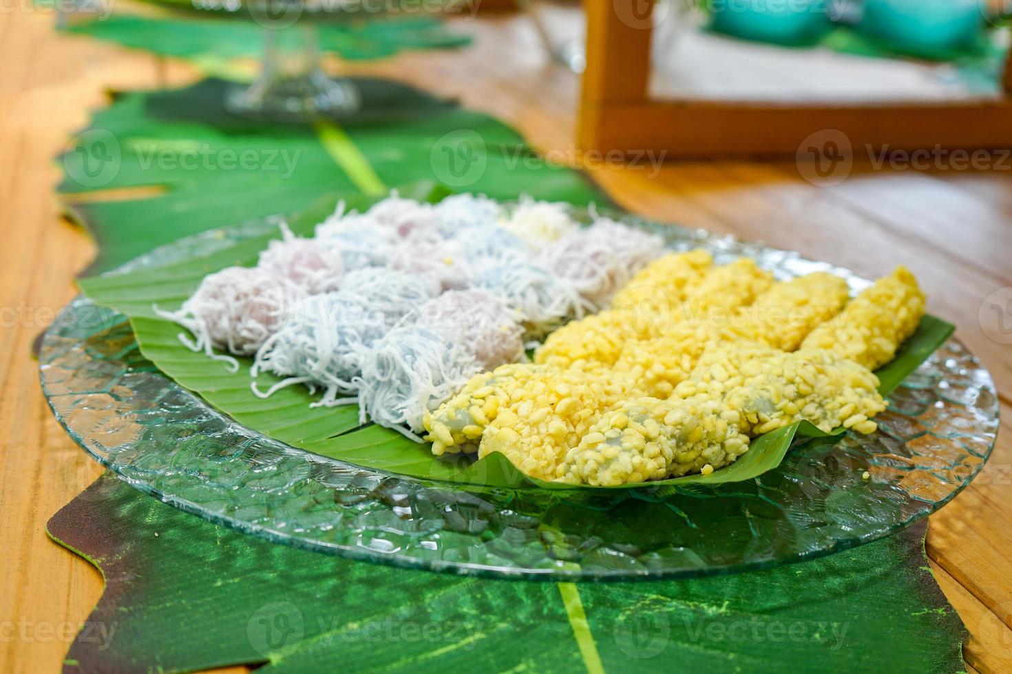 Thailand vintage dessert call mung bean rice-crepe with mung bean and coconut slide on top arranged on banana leaf in glass dish on wood table in the garden. photo