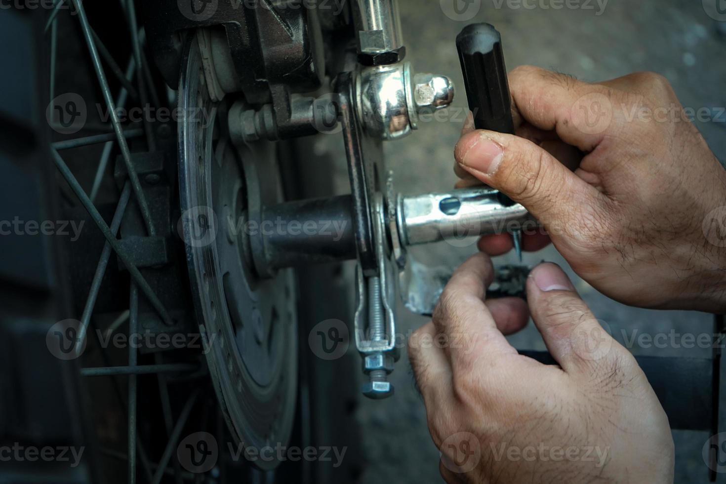 close up technician worker hand, fixed motocycle wheel at the outside of garage. photo