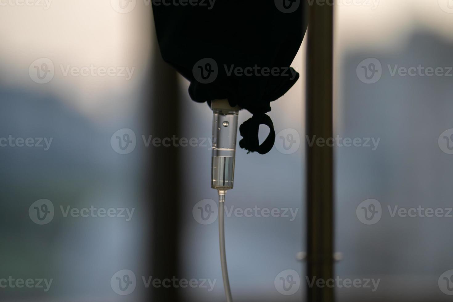 close up to the medical tool, saline drip in the dark silhouette theme on the evening window light. photo